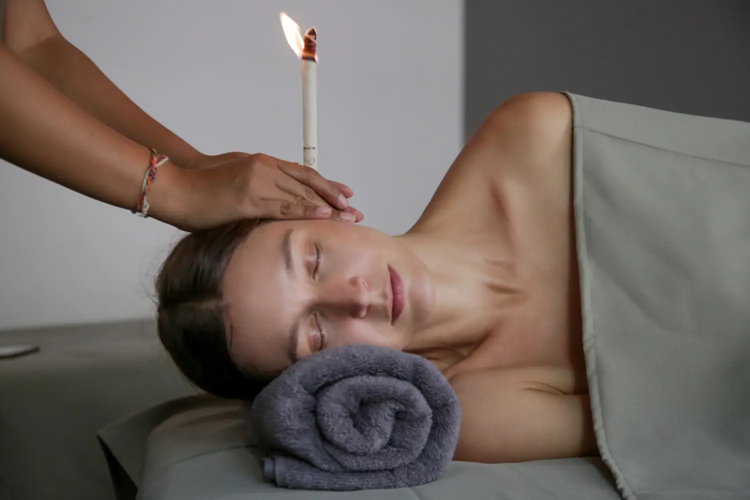 Frau bei einer Ohrkerzenbehandlung im Spa. Ohrenkoning oder thermo-aurikuläre Therapie